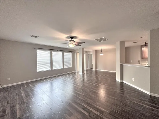 a view of a livingroom with wooden floor and a kitchen