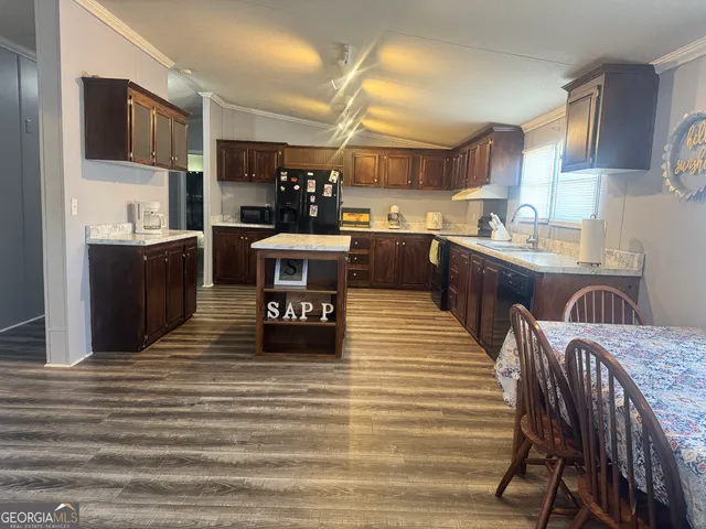 a kitchen with stainless steel appliances kitchen island granite countertop a table chairs in it and a wooden floor
