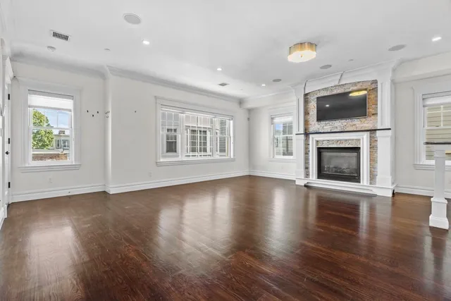 an empty room with windows fireplace and wooden floor