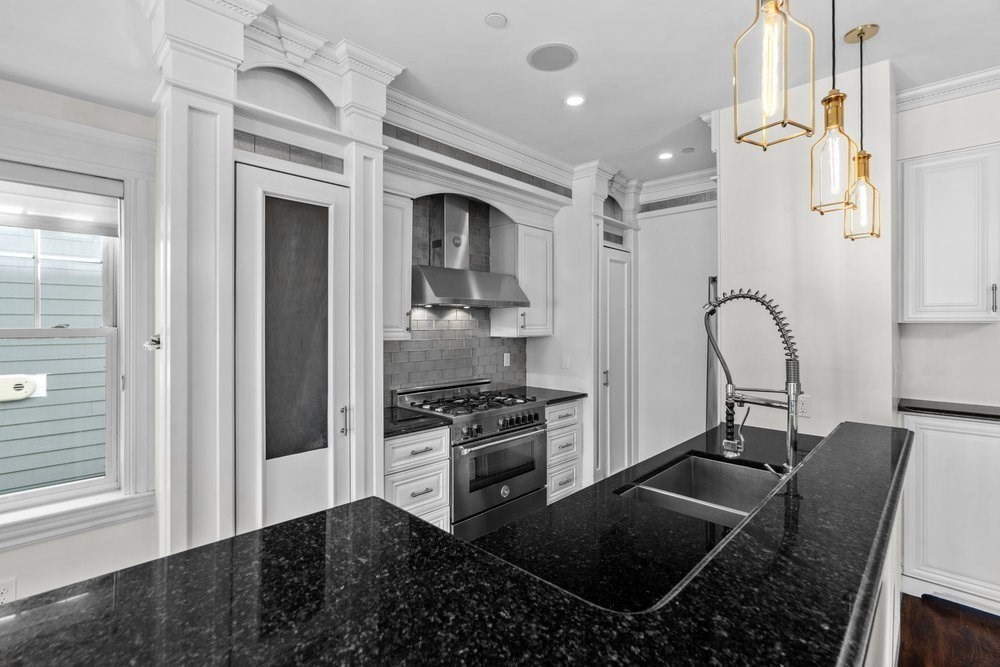 161 Tudor Street, Unit 4 Boston, MA 02127 - Photo 5 of 34 a kitchen with stainless steel appliances granite countertop a stove a sink and a refrigerator