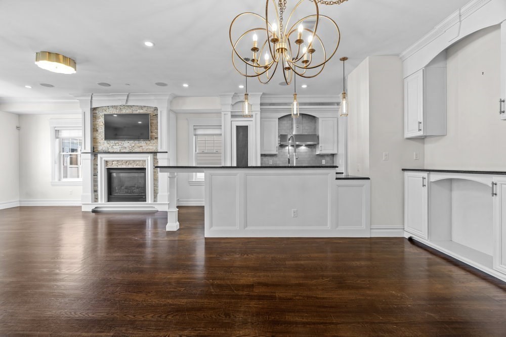 161 Tudor Street, Unit 4 Boston, MA 02127 - Photo 6 of 34 an empty room with wooden floor and a kitchen view