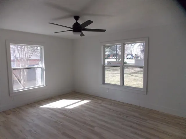 a view of an empty room with wooden floor and window