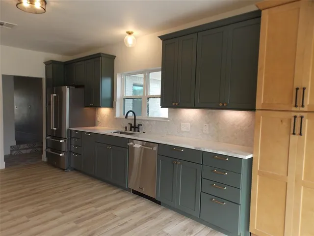 a kitchen with stainless steel appliances granite countertop a refrigerator and a sink