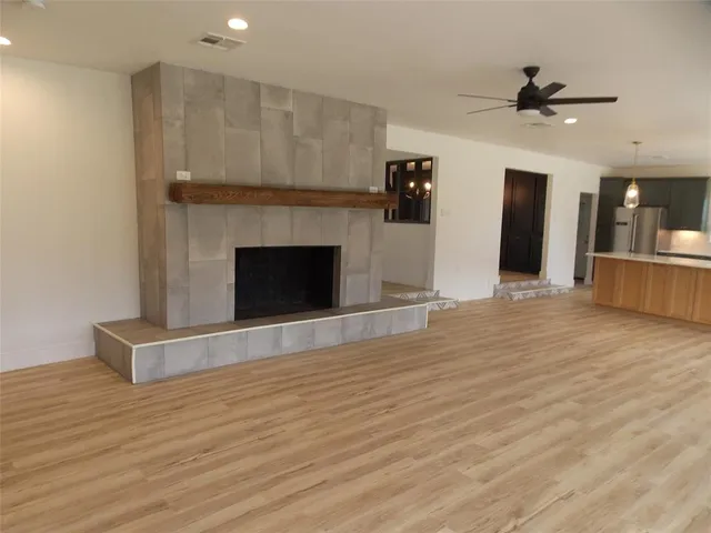a view of an empty room with wooden floor and a fireplace