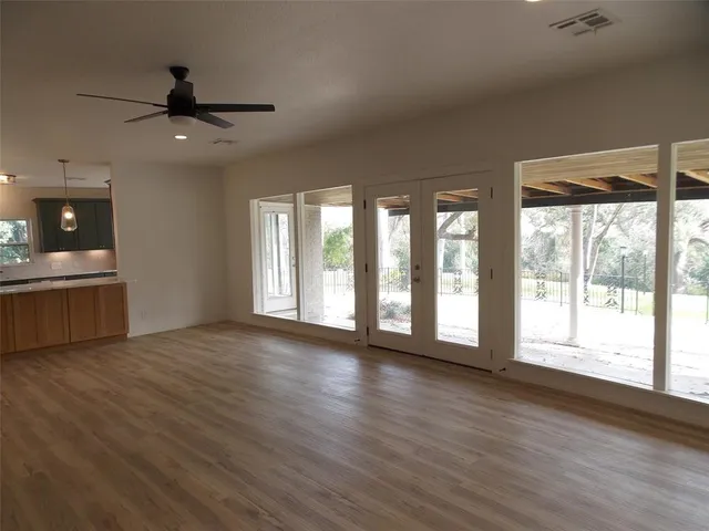 a view of an empty room with a window and wooden floor