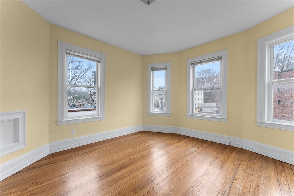 571 Washington Street, Unit 2 Boston, MA 02135 - Photo 4 of 13 a view of an empty room with wooden floor and a window