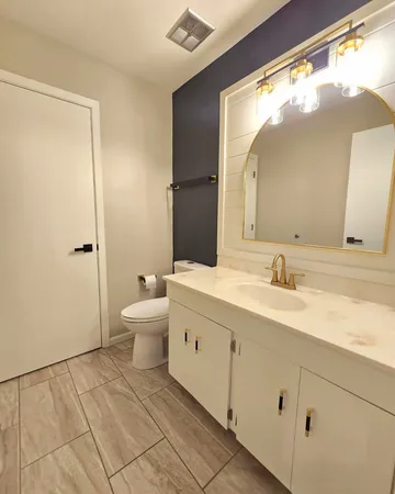 a spacious bathroom with a double vanity sink toilet mirror and shower
