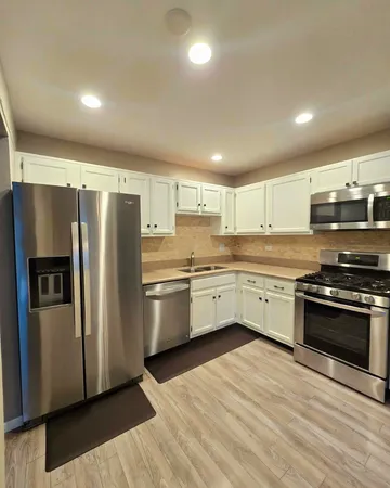 a kitchen with granite countertop a refrigerator and a stove top oven