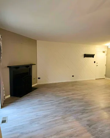 a view of an empty room with wooden floor and a fireplace