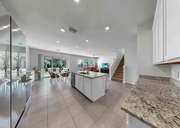 a kitchen with stainless steel appliances granite countertop a stove top oven a sink a refrigerator and white cabinets