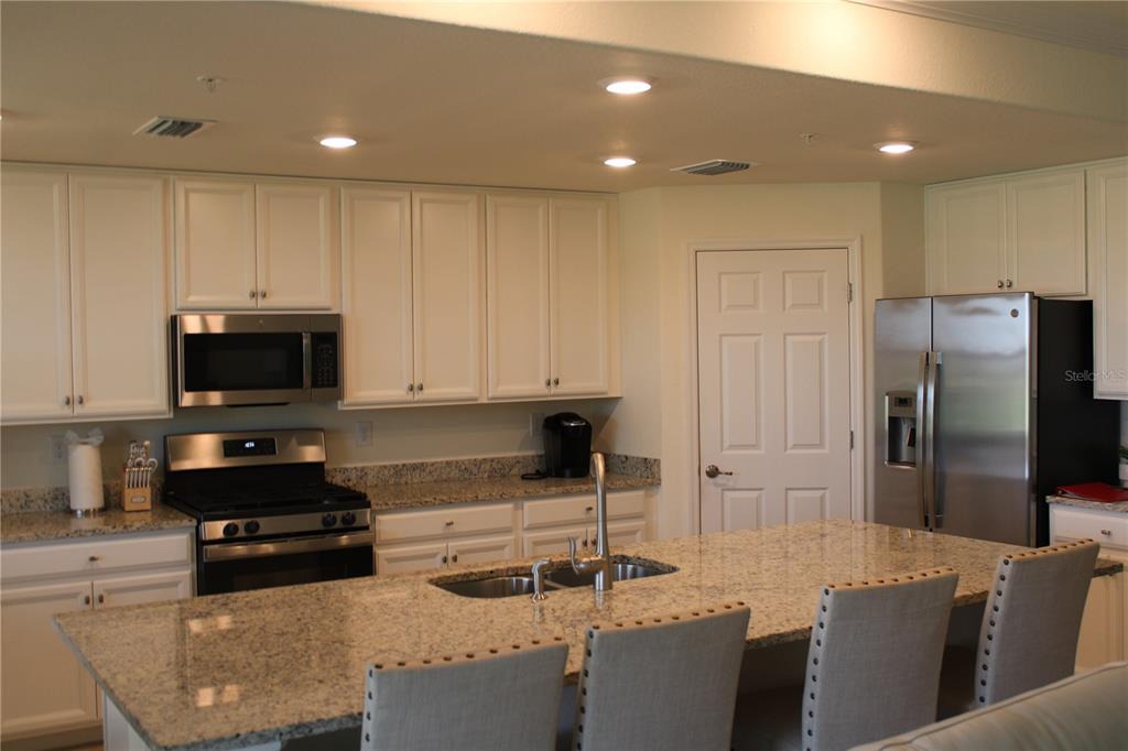 18017 Gawthrop Drive, Unit 104 Bradenton, FL 34211 - Photo 2 of 54 a kitchen with stainless steel appliances granite countertop a refrigerator a stove a sink a dining table and chairs