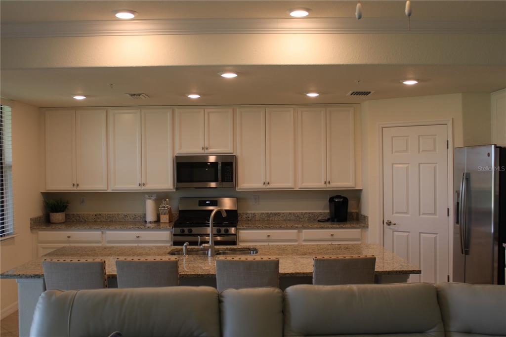 18017 Gawthrop Drive, Unit 104 Bradenton, FL 34211 - Photo 3 of 54 a living room with stainless steel appliances granite countertop a couch a sink a stove a microwave a refrigerator and cabinets