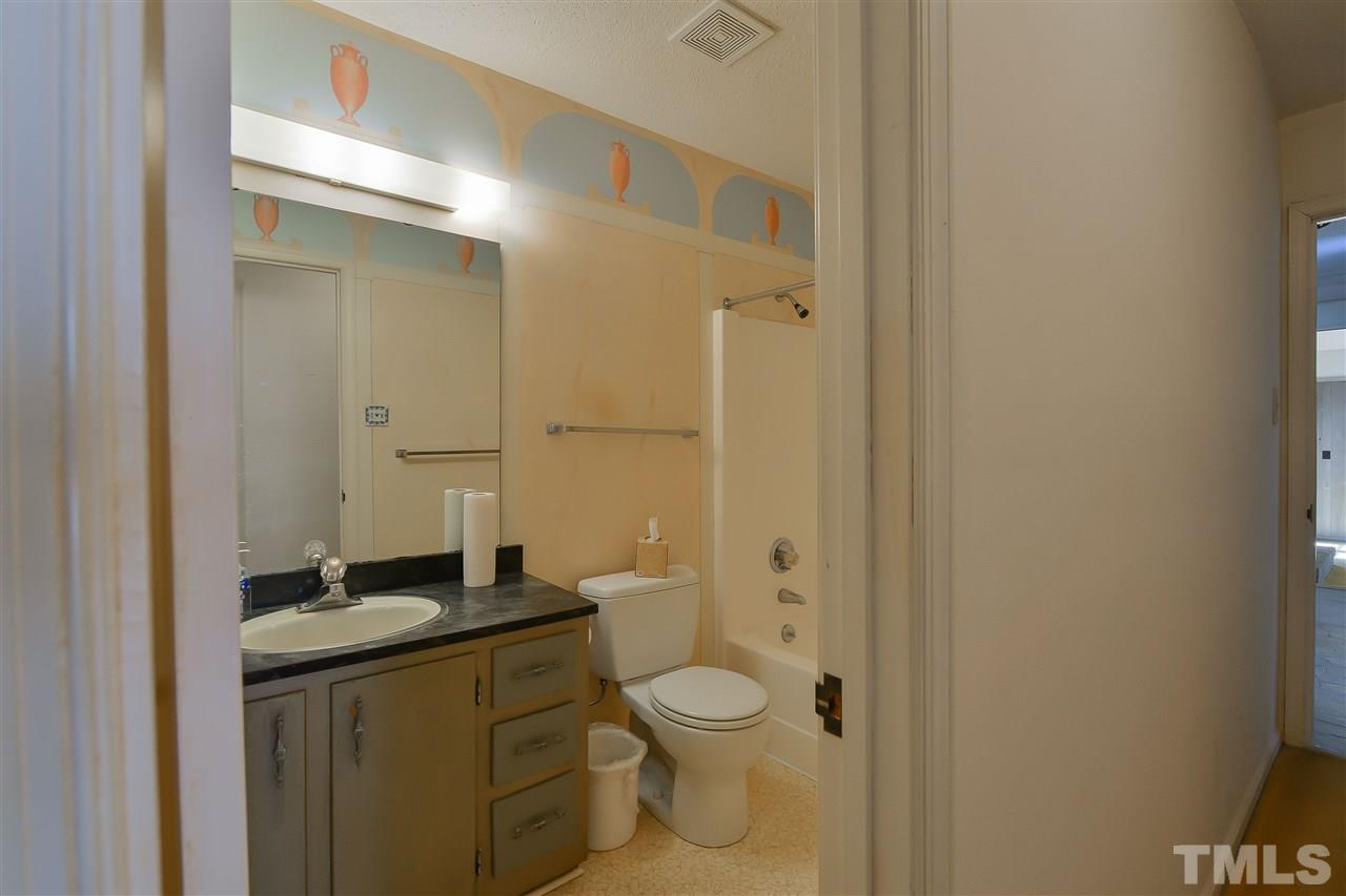 6712 Laurdane Road Raleigh, NC 27613 - Photo 14 of 25 a bathroom with a granite countertop toilet a sink and a mirror