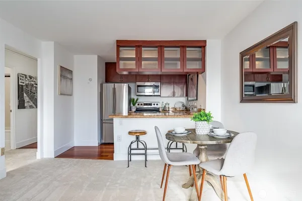 a kitchen with stainless steel appliances kitchen island granite countertop a refrigerator and a dining table