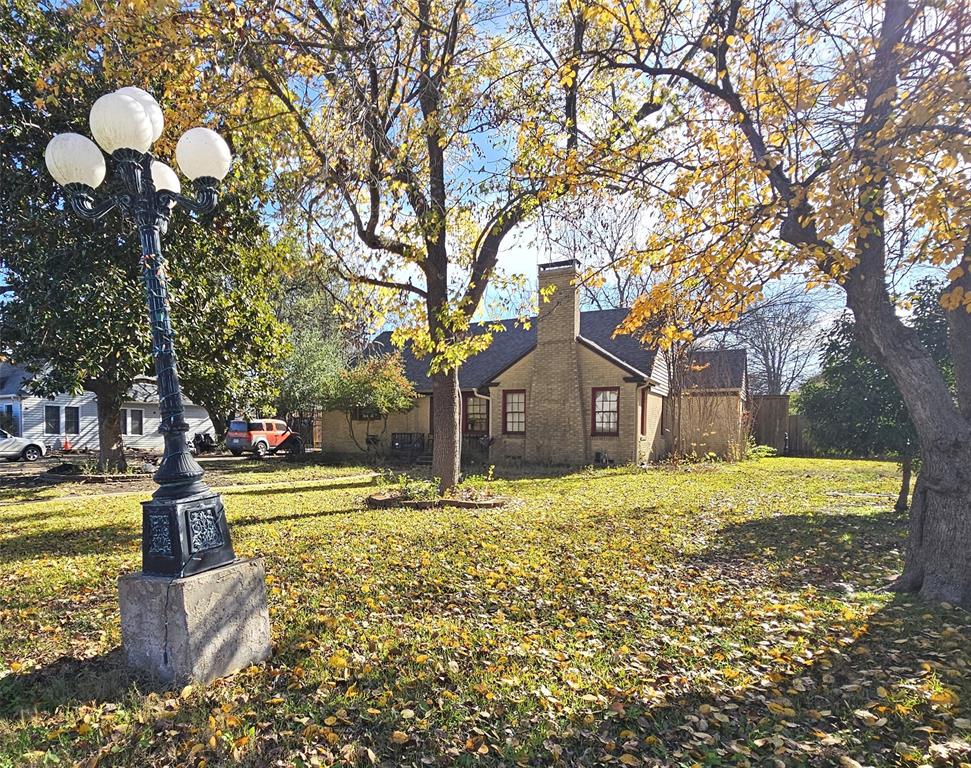 122 East 7th Street Lancaster, TX 75146 - Photo 5 of 5 View of front and side of home with a chimney, a yard, and brick siding. Light pole