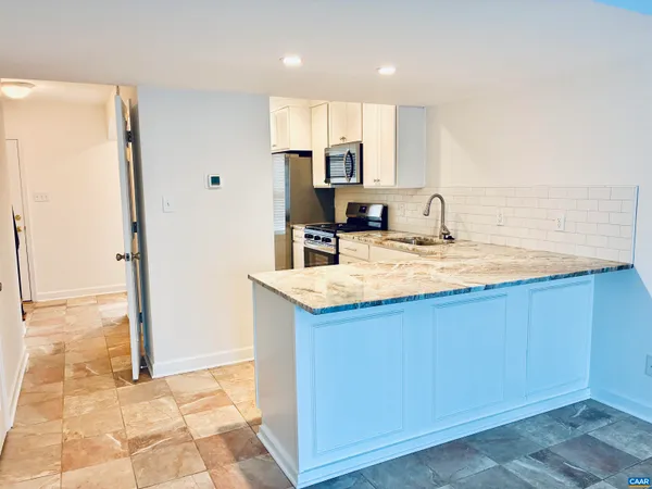 a kitchen with stainless steel appliances granite countertop a sink and a refrigerator