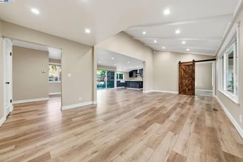 a view of an empty room with wooden floor and a bathroom