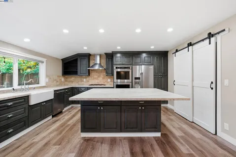 a kitchen with kitchen island granite countertop a sink appliances and cabinets