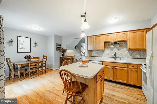 a kitchen with stainless steel appliances a dining table chairs and wooden floor