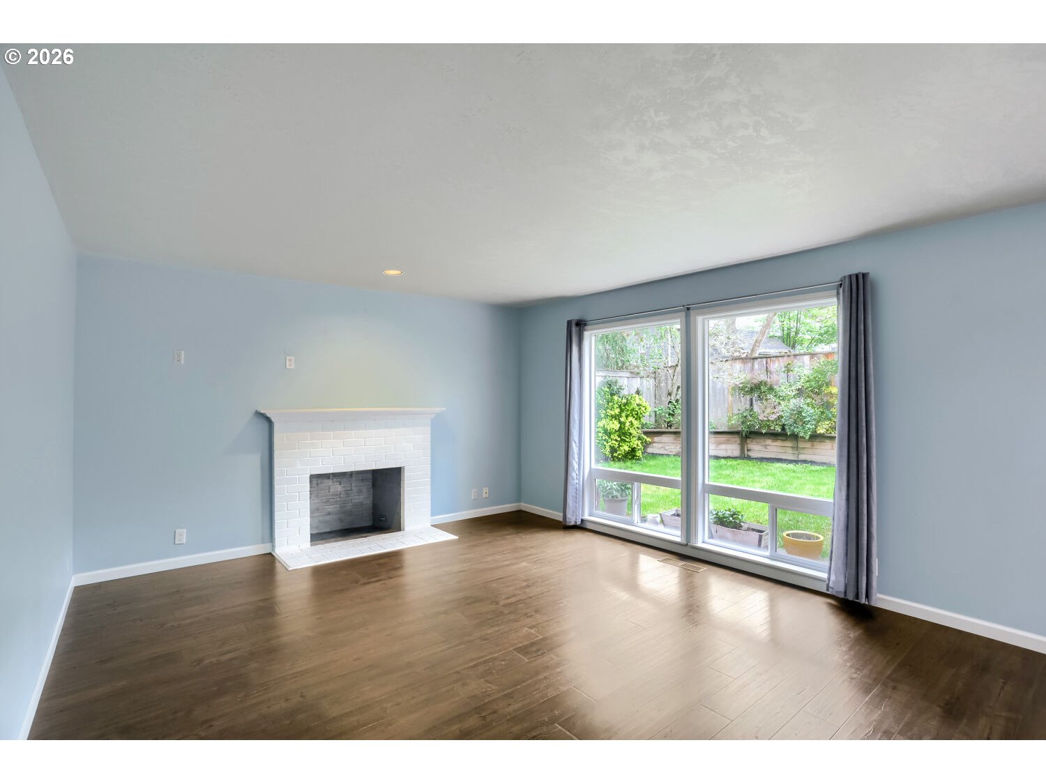 8160 Southwest 147th Terrace Beaverton, OR 97007 - Photo 9 of 31 a view of empty room with wooden floor and fireplace