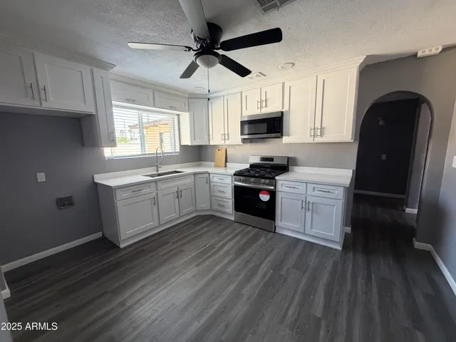 a kitchen with stainless steel appliances granite countertop a sink a stove a refrigerator cabinets and wooden floor