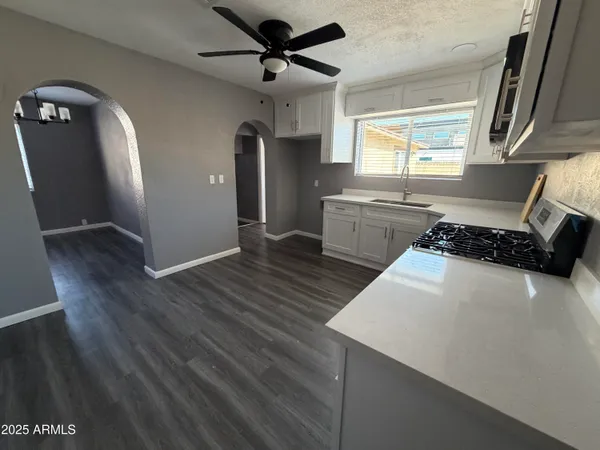 a kitchen with stainless steel appliances a refrigerator a sink a stove and wooden floor