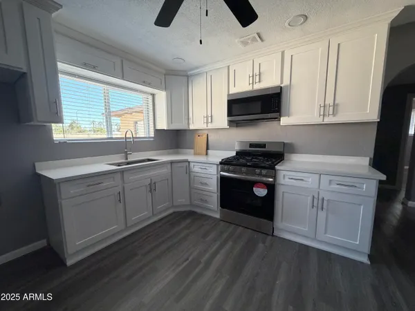 a kitchen with stainless steel appliances white cabinets a sink a stove a microwave a sink and wooden floor