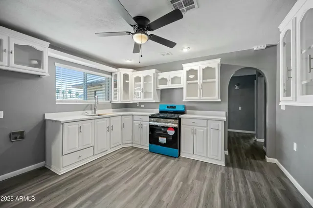 a kitchen with granite countertop a refrigerator a sink dishwasher a stove and white cabinets with wooden floor