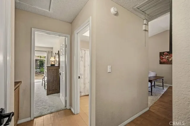 a view of a hallway with wooden floor and a bathroom