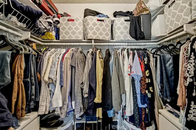 a view of walk in closet with clothes and shoes