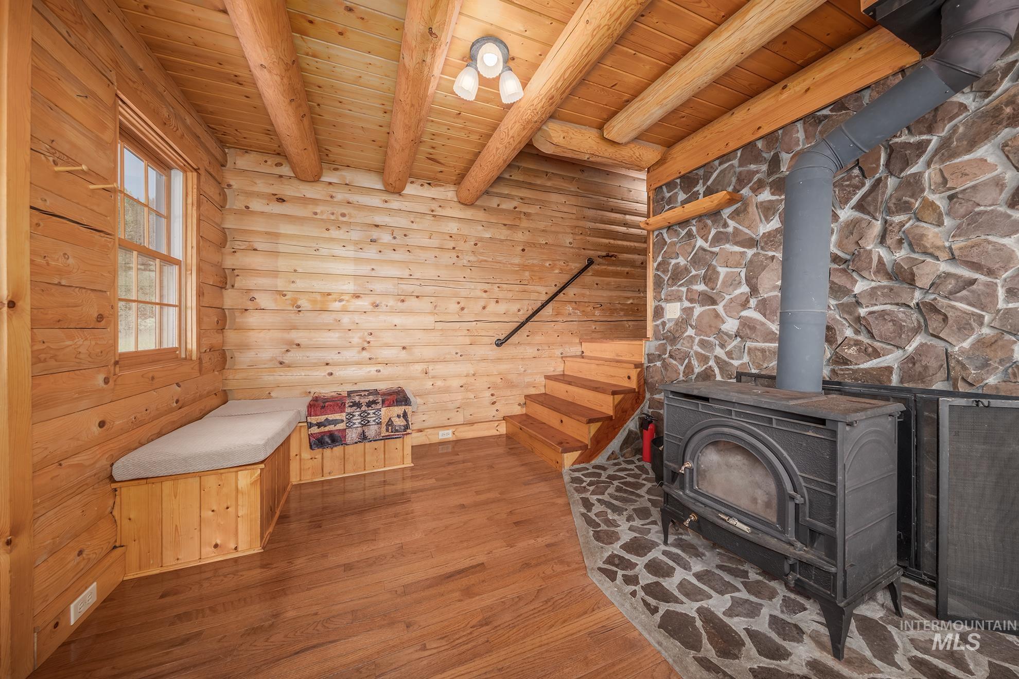 2150 Seid Creek Road Cambridge, ID 83610 - Photo 41 of 50 Interior space featuring exposed log walls, natural wood-finish flooring, and a stone accent wall
