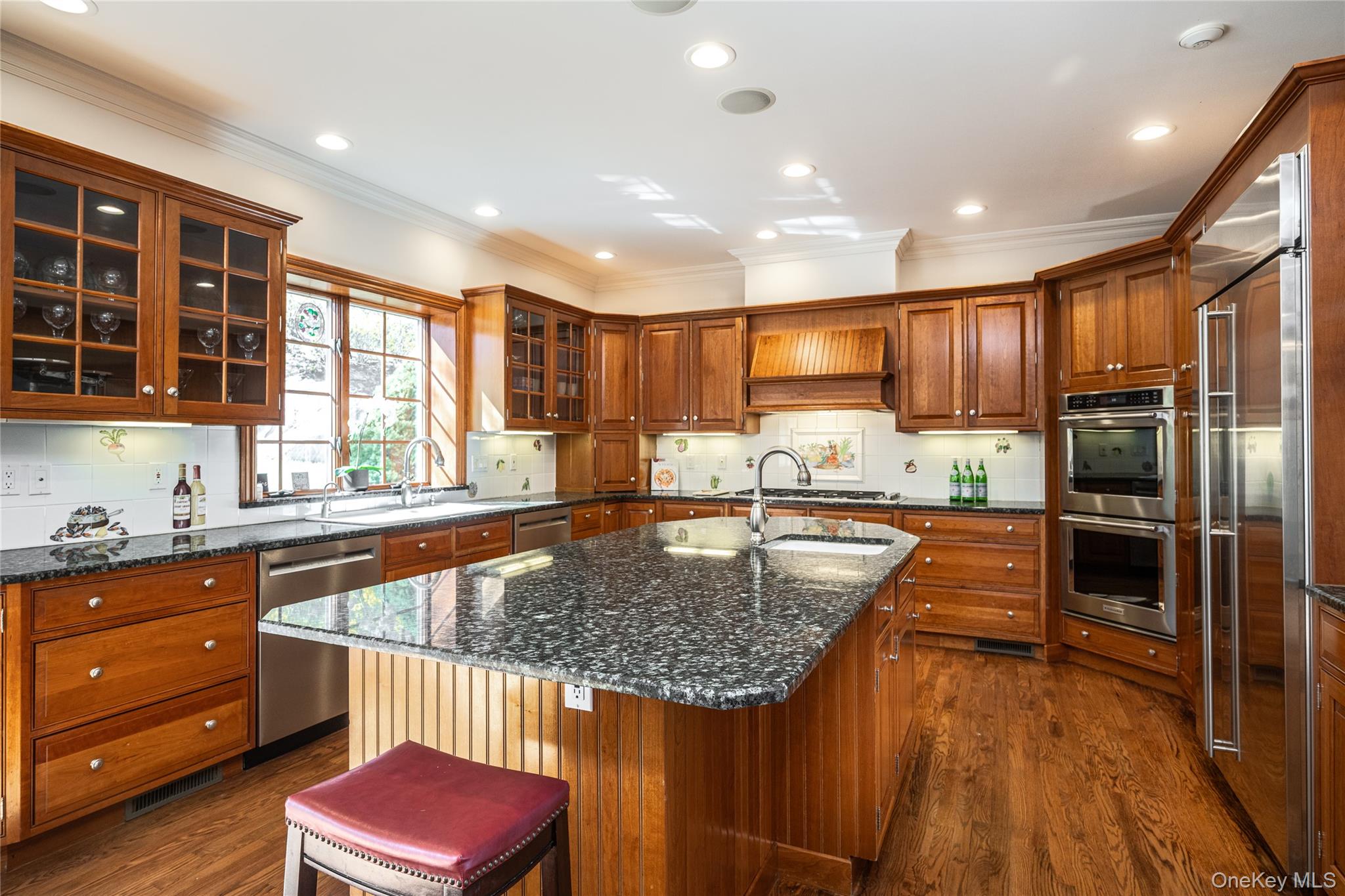 178 Hirst Road Briarcliff Manor, NY 10510 - Photo 12 of 39 Kitchen featuring backsplash, dark stone counters, a kitchen island with sink, stainless steel appliances, and wood finish cabinets