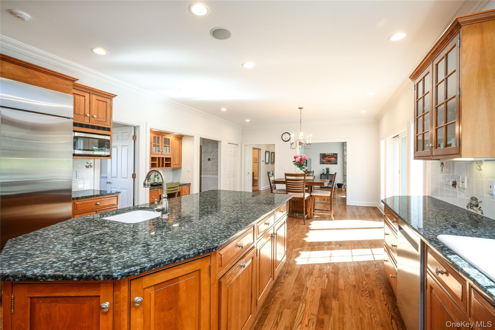 178 Hirst Road Briarcliff Manor, NY 10510 - Photo 10 of 39 Kitchen with glass fronted cabinets, light wood-style flooring, wood finish cabinets, dark stone counters, and crown molding