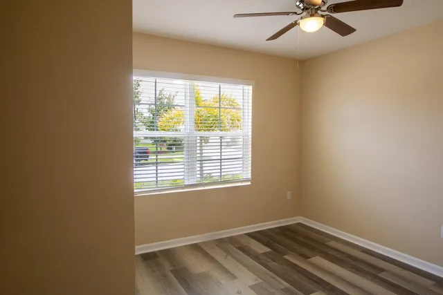 a view of an empty room with a window and a dresser