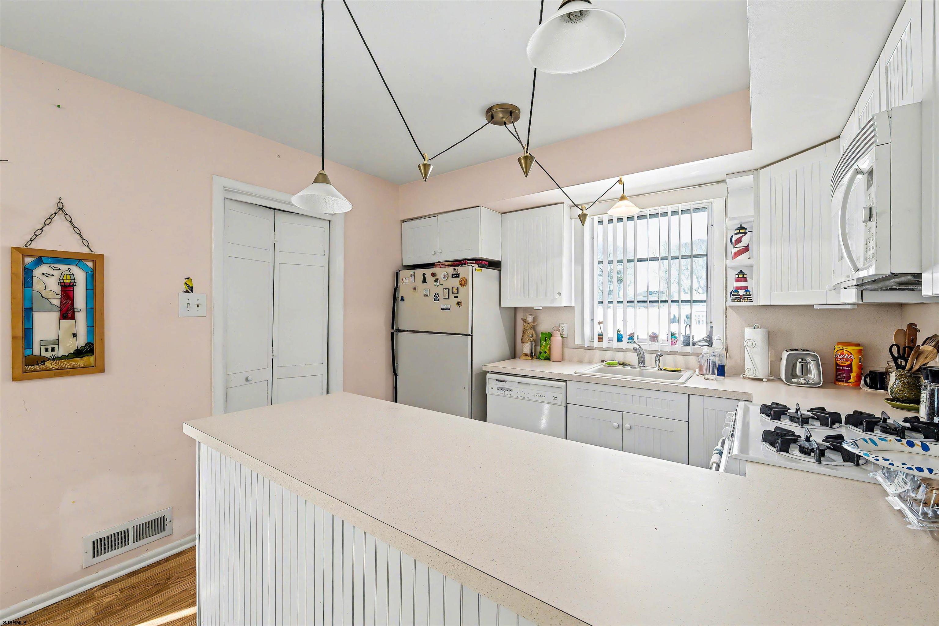 116 Haddon Road Somers Point, NJ 08244 - Photo 11 of 21 a kitchen with kitchen island a refrigerator a stove a sink dishwasher and white cabinets with wooden floor