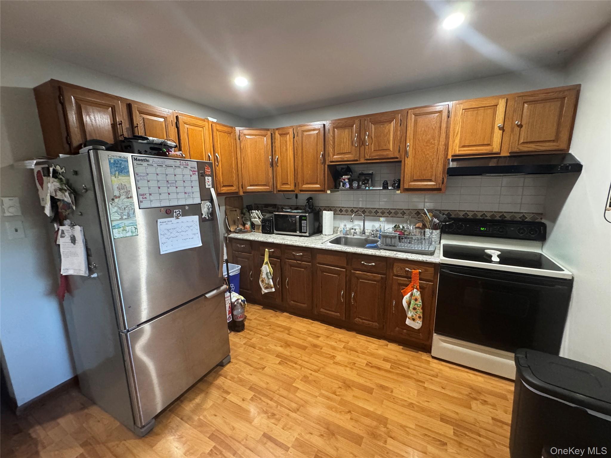 131 Ferndale Road Ferndale, NY 12734 - Photo 9 of 20 Wood-finish flooring, wood cabinetry, stainless steel refrigerator, white tile backsplash, and recessed lighting