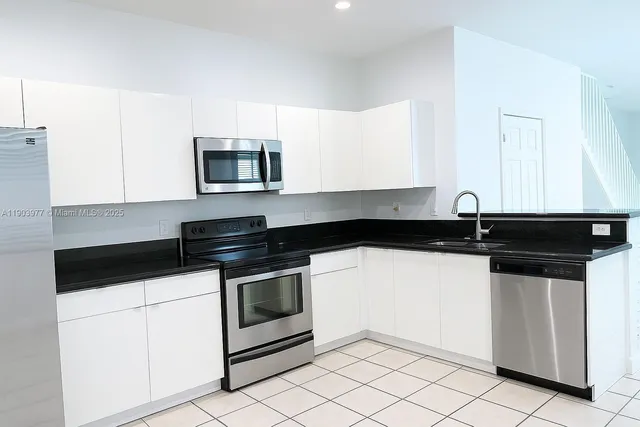 a kitchen with granite countertop white cabinets and black appliances