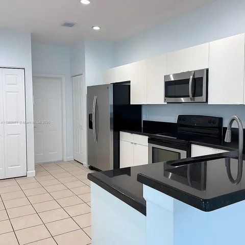 a kitchen with stainless steel appliances granite countertop a refrigerator a stove and a sink