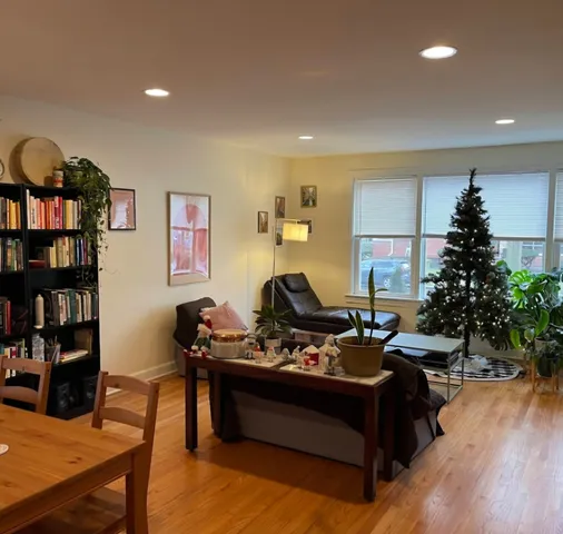 a living room with furniture and a bookshelf with wooden floor