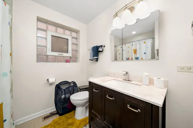 a bathroom with a toilet sink vanity and mirror