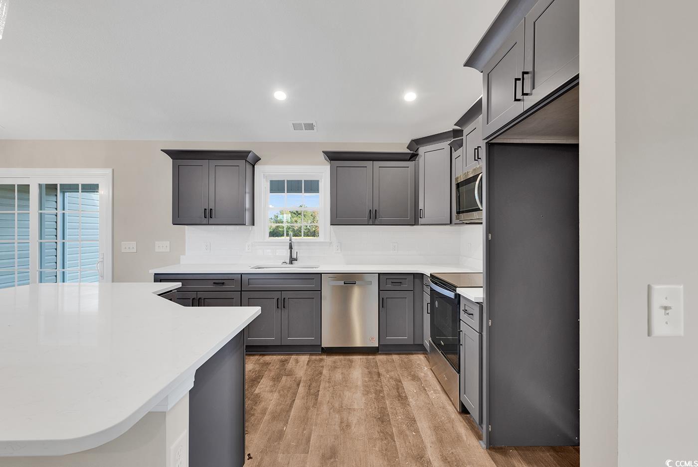 3261 Red Bluff Road Loris, SC 29569 - Photo 14 of 39 Kitchen with gray cabinetry, light wood finished floors, stainless steel appliances, recessed lighting, and decorative backsplash
