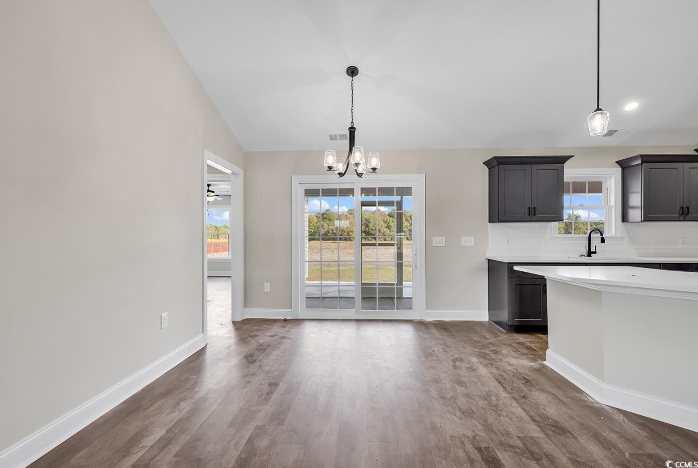3261 Red Bluff Road Loris, SC 29569 - Photo 15 of 39 Kitchen featuring dark wood-type flooring, pendant lighting, a chandelier, decorative backsplash, and light stone countertops