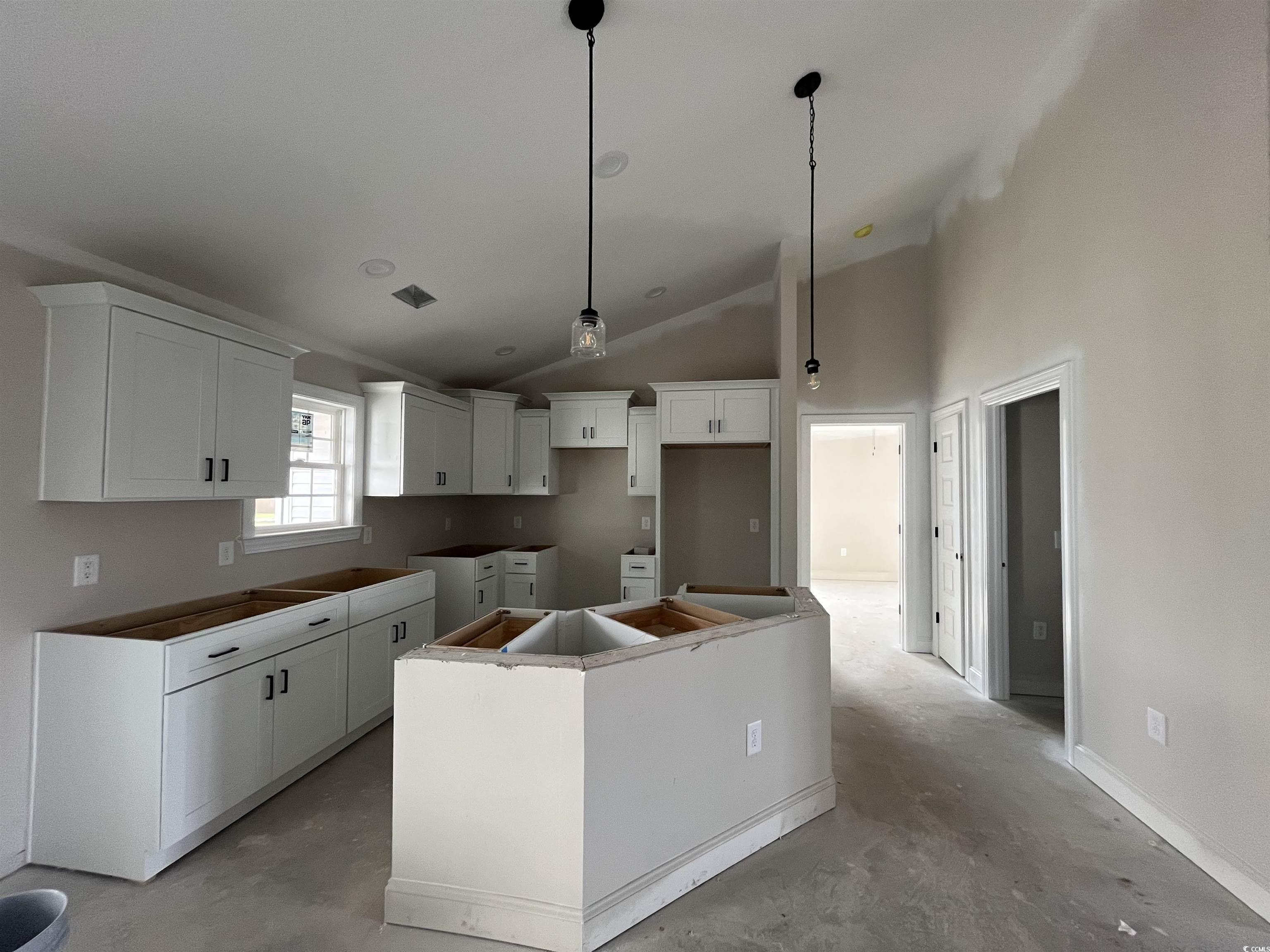 3261 Red Bluff Road Loris, SC 29569 - Photo 3 of 39 Kitchen with a center island, high vaulted ceiling, decorative light fixtures, concrete floors, and white cabinets