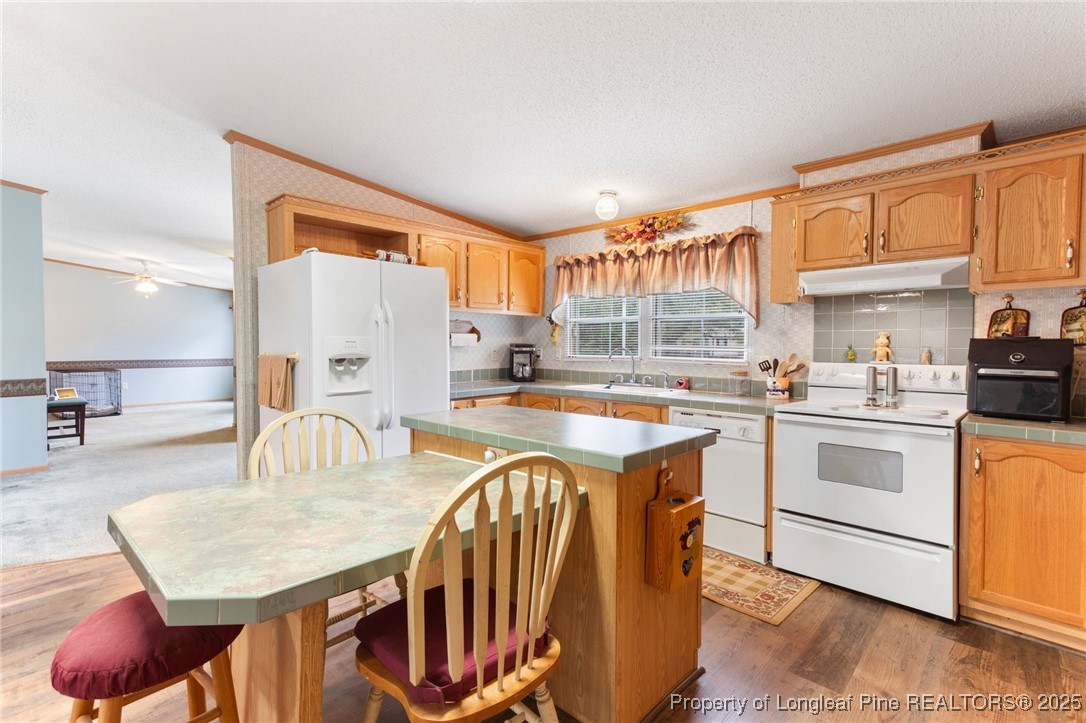 520 Inverary Drive Raeford, NC 28376 - Photo 14 of 43 a kitchen with stainless steel appliances granite countertop a stove top oven a sink a dining table and chairs with wooden floor