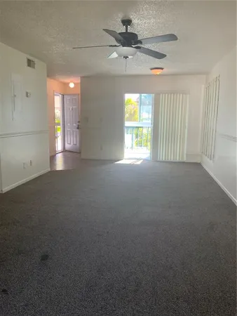 en empty room with windows and ceiling fan