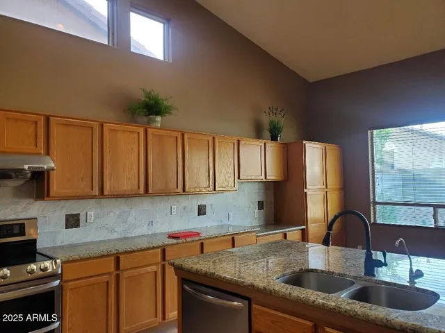 a kitchen with granite countertop a sink a stove and cabinets