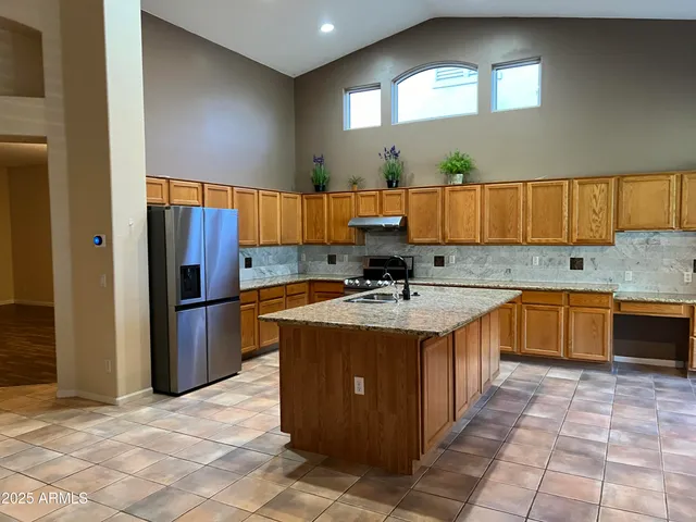 a kitchen with stainless steel appliances granite countertop a sink a stove a refrigerator a center island and cabinets
