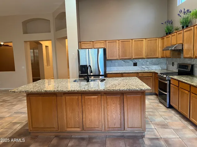 a kitchen with kitchen island granite countertop a sink a counter top space and cabinets