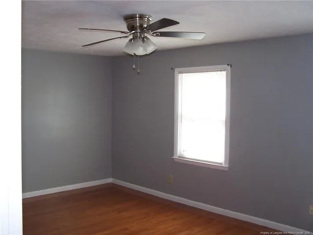an empty room with a window and a fan