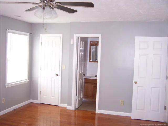 an empty room with wooden floor closet and windows